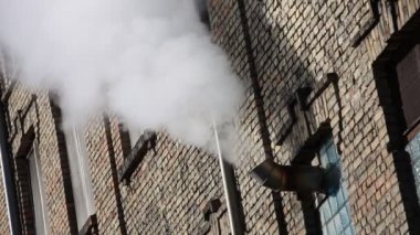 Beyaz Buhar eski bir tuğla duvardaki havalandırmadan çıkıyor.