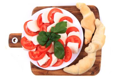 Geleneksel domates ve mozzarella yemeklerini fesleğenle kaplayın.