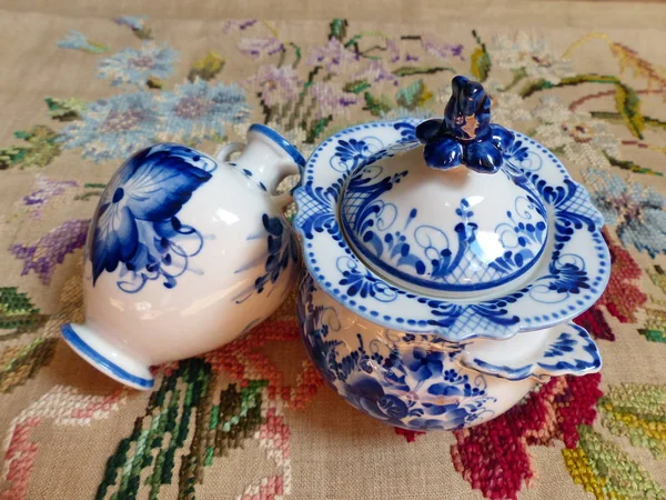 Sugar bowl and a vase, linen tablecloth. Things in Russian traditional Gzhel style. Closeup. Gzhel - Russian folk craft of ceramics and production porcelain and a kind of Russian folk painting.
