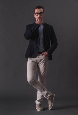 Takım elbise ve gri arka plan üzerinde kamera bakarak gözlük yakışıklı genç işadamı tam boy görüntü