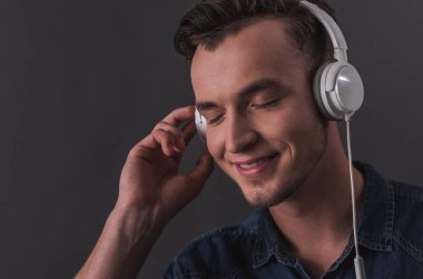 Kulaklığımda yakışıklı genç gri arka plan üzerinde müzik dinleme