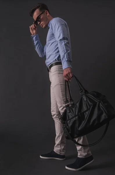 スマート カジュアルな服と灰色の背景に 袋を保持するガラスのスタイリッシュな青年実業家のフルの長さの画像 — ストック写真