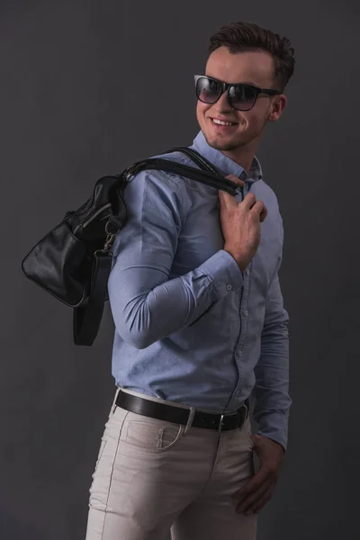 Elegantní Mladý Podnikatel Neformálním Oblečení Brýle Drží Pytel Usmíval Šedém — Stock fotografie