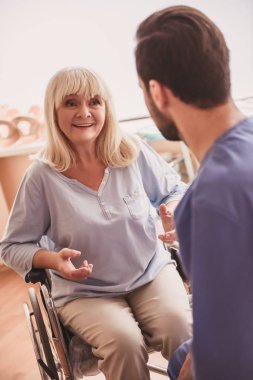 Güzel eski Bayan doktorla konuşmak ve hastane koğuşunda tekerlekli sandalyede otururken gülümseyen