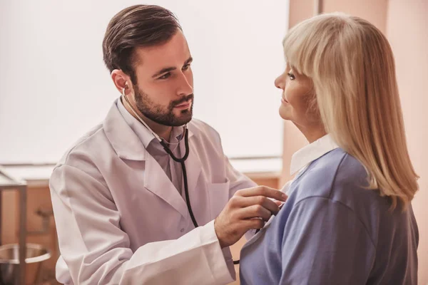 Apuesto Doctor Está Escuchando Latido Del Corazón Una Anciana Usando — Foto de Stock