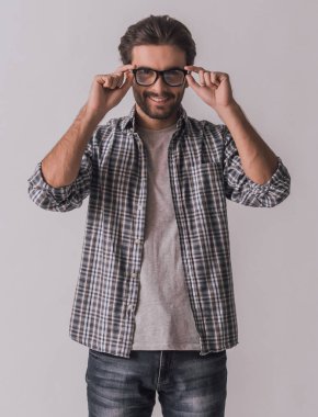 Rahat kıyafetler içinde yakışıklı sakallı adam kameraya bakıyor ve gülümsüyor, açık renkli gözlük, koyuyor