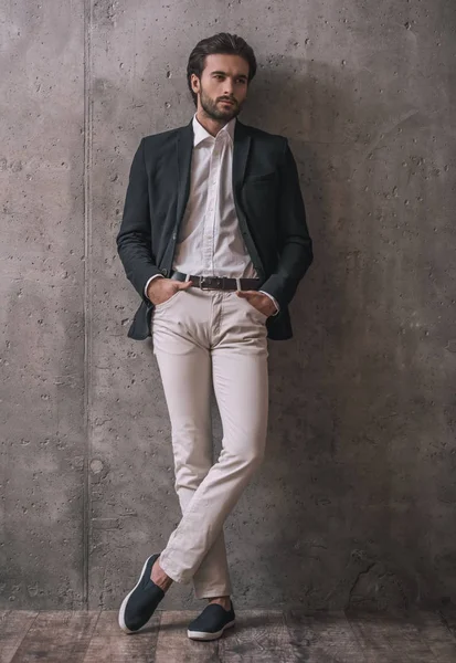 Gri arka plan üzerinde kamera poz yakışıklı emin işadamı ile kıl, takım, tam uzunlukta portresi