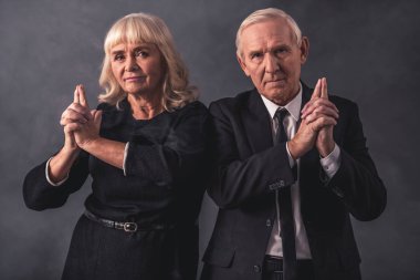 Şık giysileriyle güzel eski çift silah, gri arka plan üzerinde taklit elele