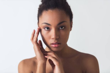 Güzel Afro-Amerikan Kız onun yüzüne dokunmaktan ve üzerinde beyaz izole kamera bakıyor