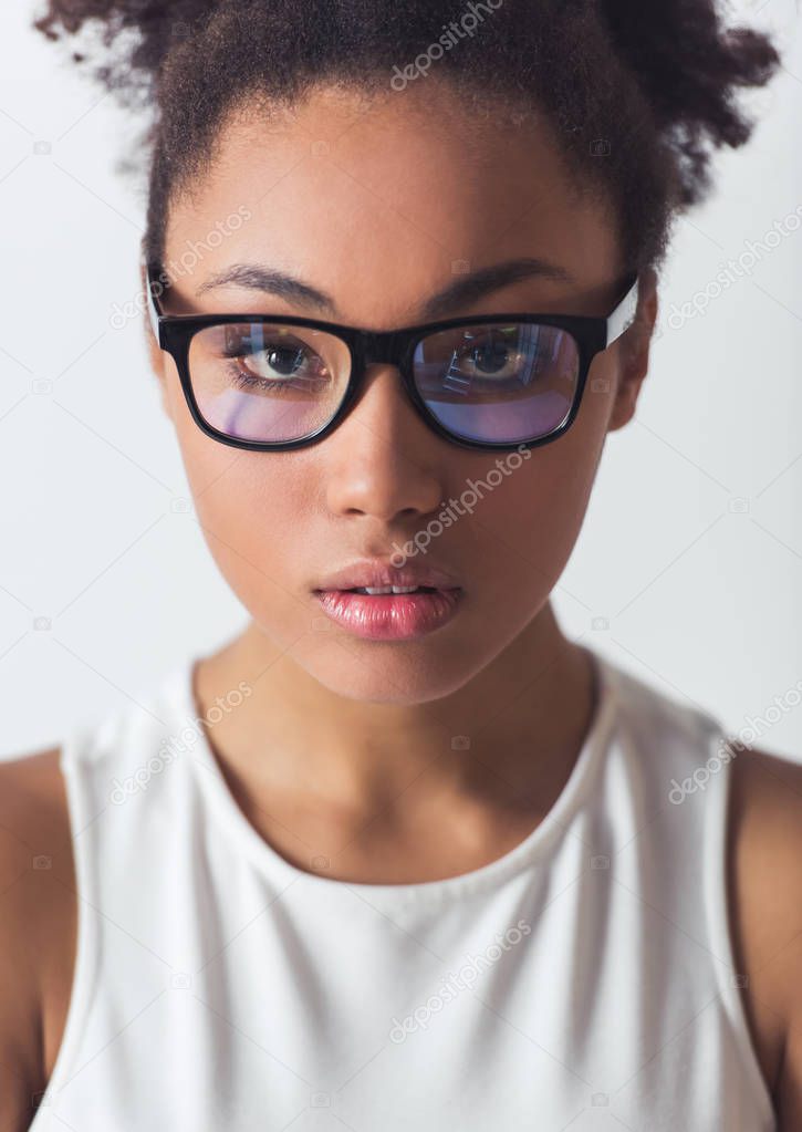 Portrait of beautiful Afro-American girl in eyeglasses looking at camera, isolated on white