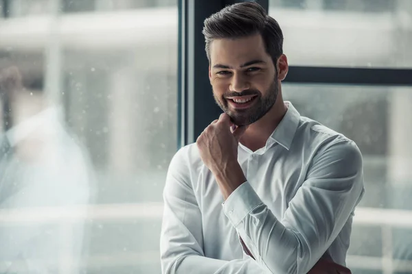 Schöner Geschäftsmann Blickt Die Kamera Berührt Sein Kinn Und Lächelt — Stockfoto