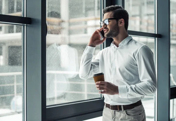 Bonito Empresário Óculos Está Falando Celular Bebendo Café Enquanto Olha — Fotografia de Stock