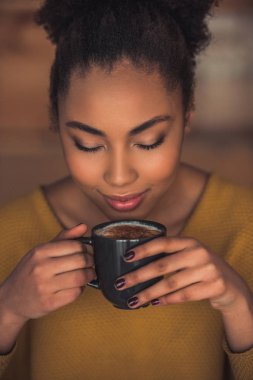 Afro Amerikan Kız güzel rahat kıyafetler kahve kokulu ve kafede istirahat ederken gülümseyen