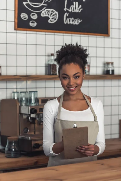 Schöne Afroamerikanische Barista Schürze Schreibt Eine Bestellung Auf Blickt Die — Stockfoto