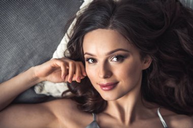 Kameraya bakarak ve evde yatakta yatan süre gülümseyen güzel genç kız portresi