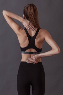 Spor giyim gri arka plan üzerinde omurgasını dokunmadan güzel kızı arkadan görünüm
