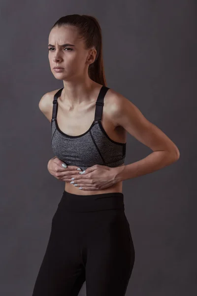 Schönes Mädchen Sportbekleidung Berührt Ihren Bauchschmerz Auf Grauem Hintergrund — Stockfoto