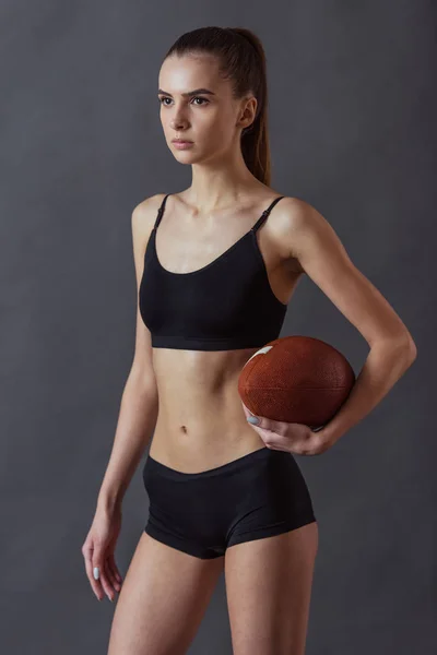 Piękna Dziewczyna Sportowej Trzyma Piłkę Futbolu Amerykańskiego Szarym Tle — Zdjęcie stockowe