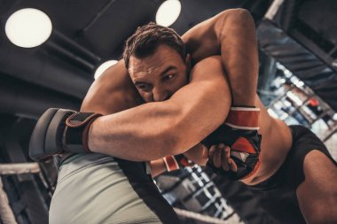 İki adam boks eldivenleri ve şort filika tekniği kullanarak kafes içinde mücadele ediyoruz