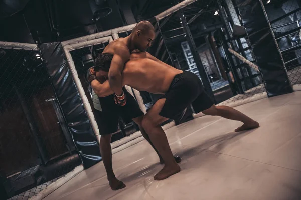 拳击手套和短裤的两个男人用格斗技术在笼子里打架 — 图库照片