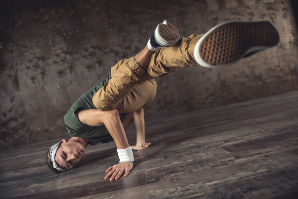 Young man break dancing on the wall background, performing tricks