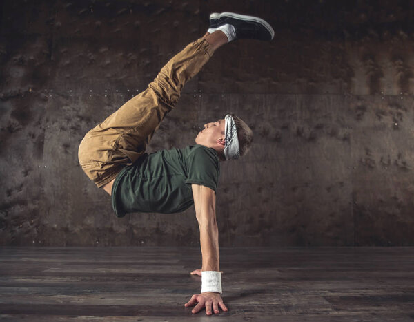 Young man break dancing on the wall background, performing tricks