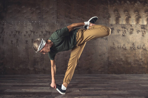 Young man break dancing on the wall background, performing tricks
