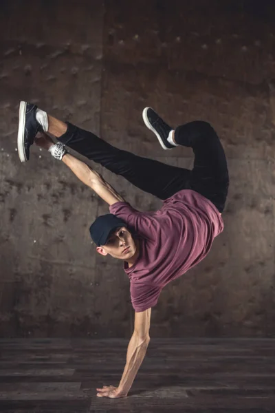 Young man break dancing on the wall background, performing tricks