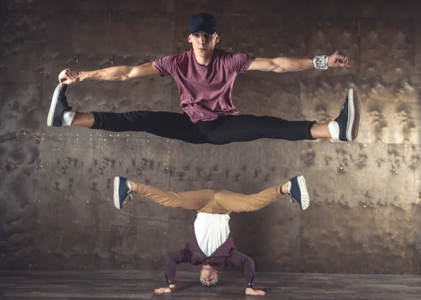 Young men break dancing on the wall background, performing tricks