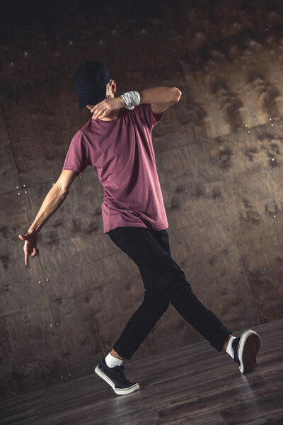 Young man break dancing on the wall background, performing tricks