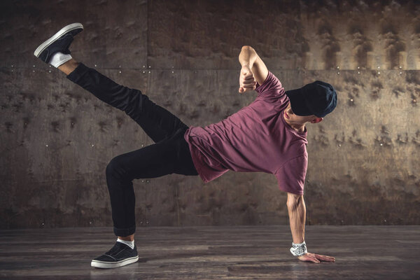 Young man break dancing on the wall background, performing tricks