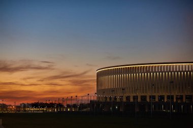 Gün batımında kırmızı ve mavi bulutlarla büyük ve büyük bir stadyum
