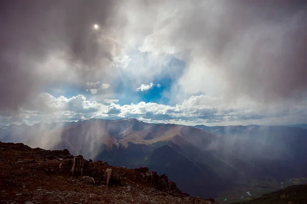 rain in the mountains with breaking rays of the sun from the clouds. High quality photo