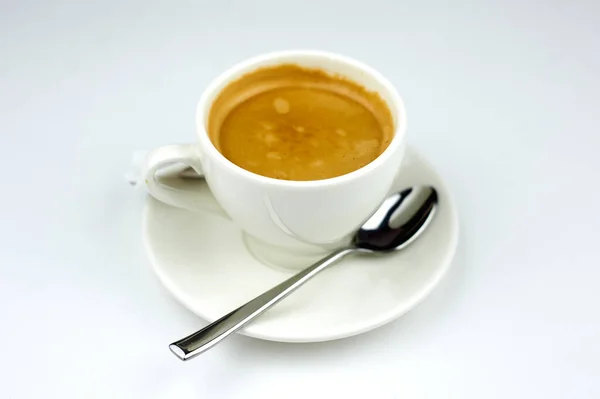 Café em uma placa branca com uma colher em um fundo branco — Fotografia de Stock