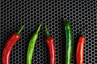 Dikey koyu arkaplanda baharatlı kırmızı ve yeşil biber