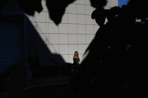 Menina de pé perto da parede com as costas para a câmera filmada horizontalmente — Fotografia de Stock