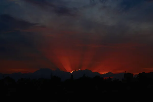 Rode zonsondergang door wolken aan de blauwe lucht horizontaal — Stockfoto