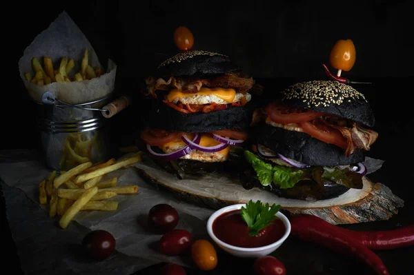 Close-up of burgers and fries in a bucket on a dark background with tomato sauce — Stock Photo, Image