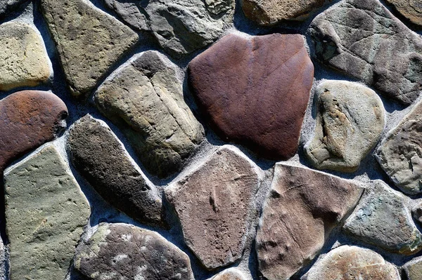 De diferentes pedras e tamanhos, a parede de pedra é muito close-up horizontalmente — Fotografia de Stock