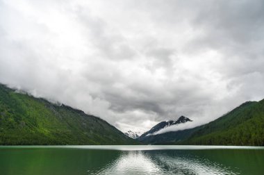 Altai Dağları 'nda göl bulutlarda gökyüzü ve dağların yeşil yamaçlarında