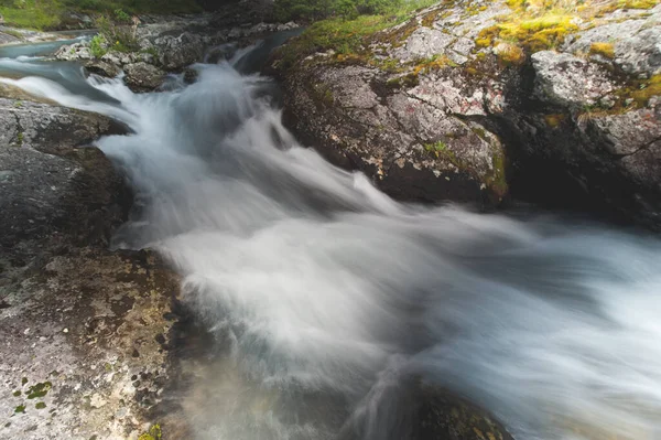 Řeka teče rychle z hor kolem kamenného břehu zblízka — Stock fotografie