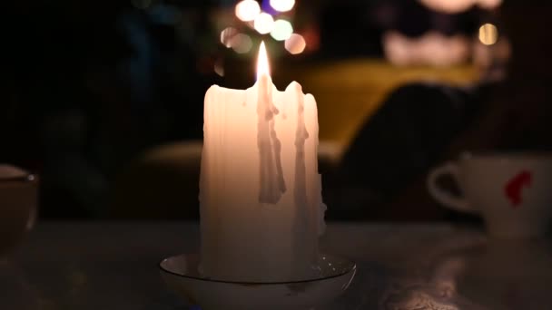 Auf dem Tisch brennt eine weiße große Kerze langsam Nahaufnahme Video 4k — Stockvideo