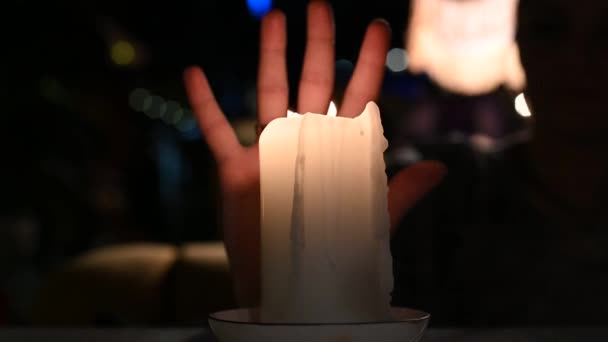 Una gran vela arde en una mesa en medio de un primer plano de la mano de vídeo 4K — Vídeos de Stock