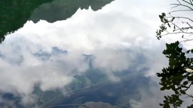 Gökyüzü bulutlarla gölün suyuna yansıyor. Yakın çekim 4k