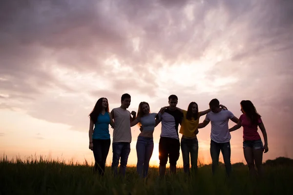 Silhouettes of people stand with their backs against the beautiful sunset sky