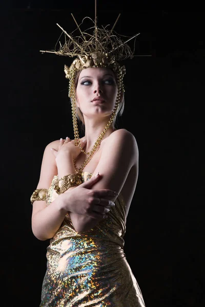 Young beautiful woman in a gold dress and crown
