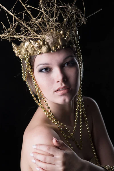 Young beautiful woman in a gold dress and crown