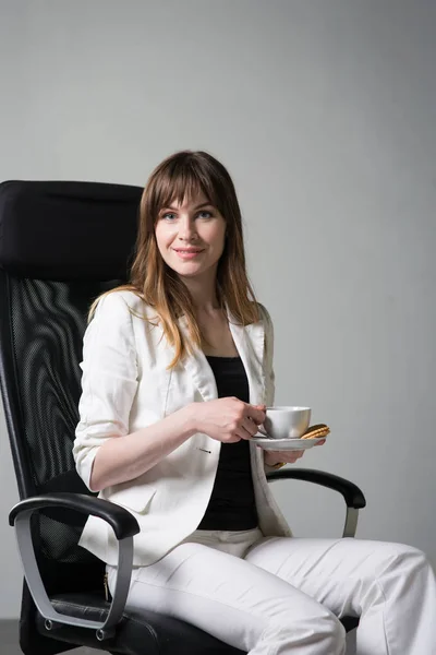Businesswoman sits on a chair on a gray background