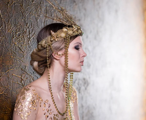 Young beautiful woman in a gold dress and crown