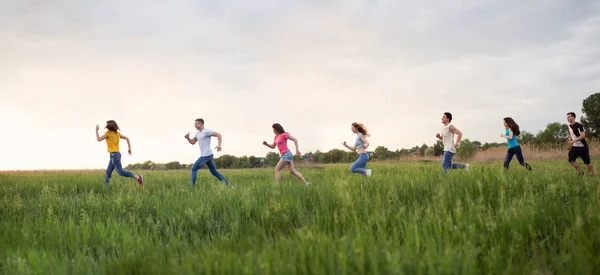 Group of people running in the grass, young people running around the field